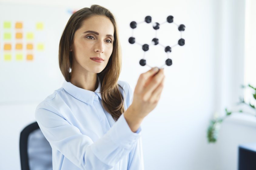 Young female scientist looking at graphene model